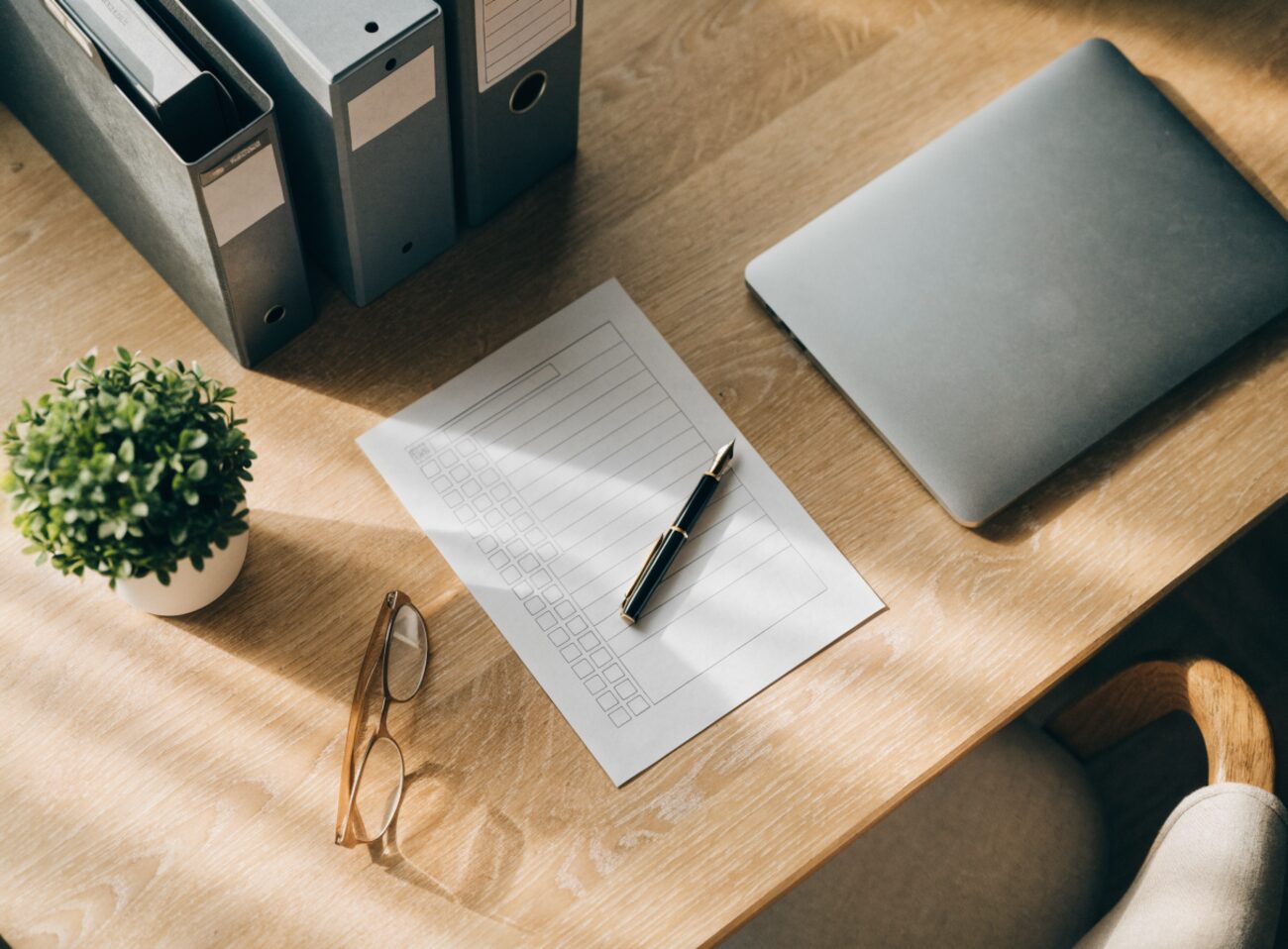 A calm, organized home desk with tidy divorce paperwork, a checklist, and a small plant in soft morning light